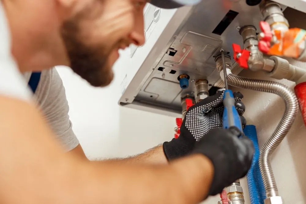Geer Plumbing Solutions technician servicing a water heater